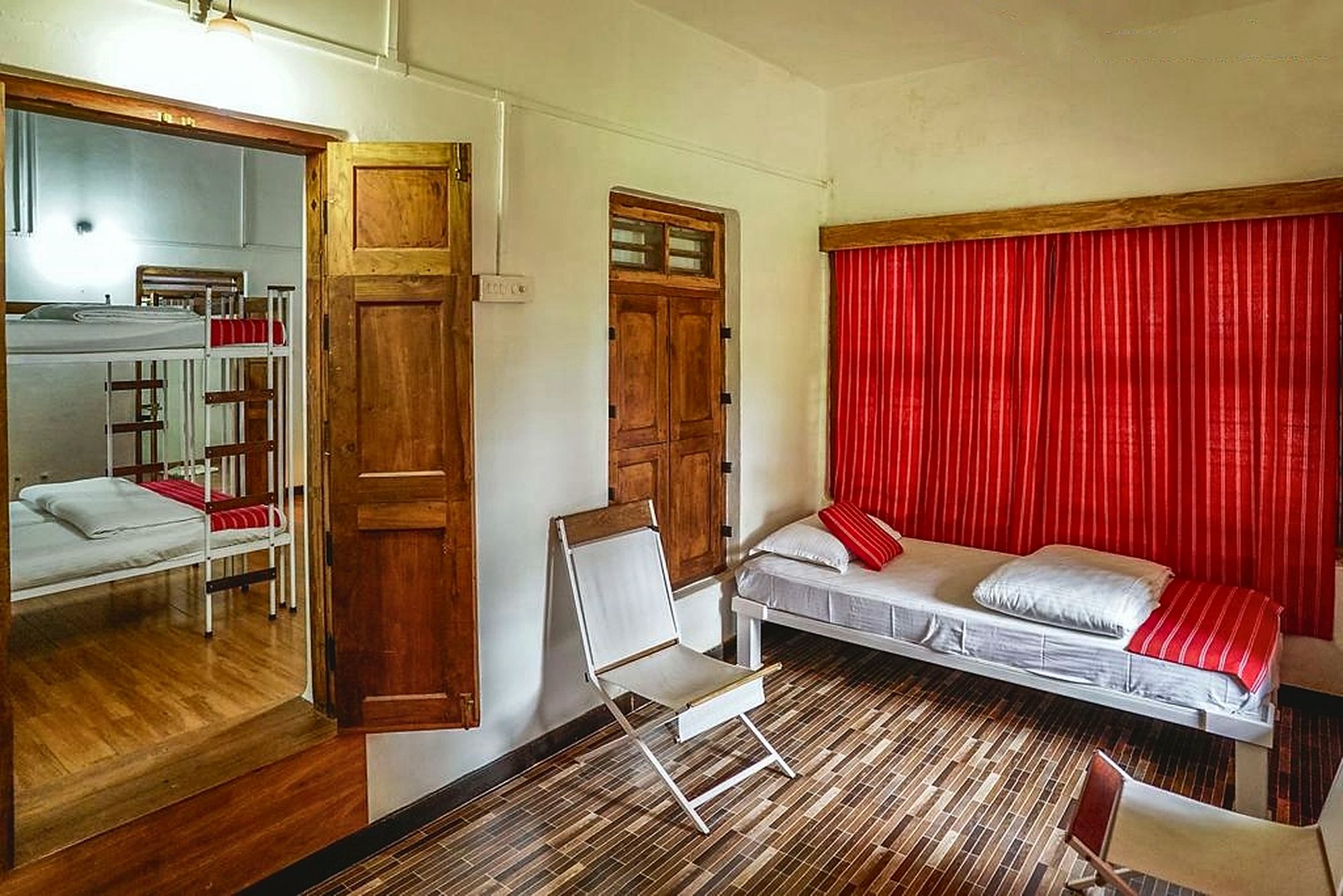 Guest room with panelled wooden doors and shutters, a daybed and red curtains