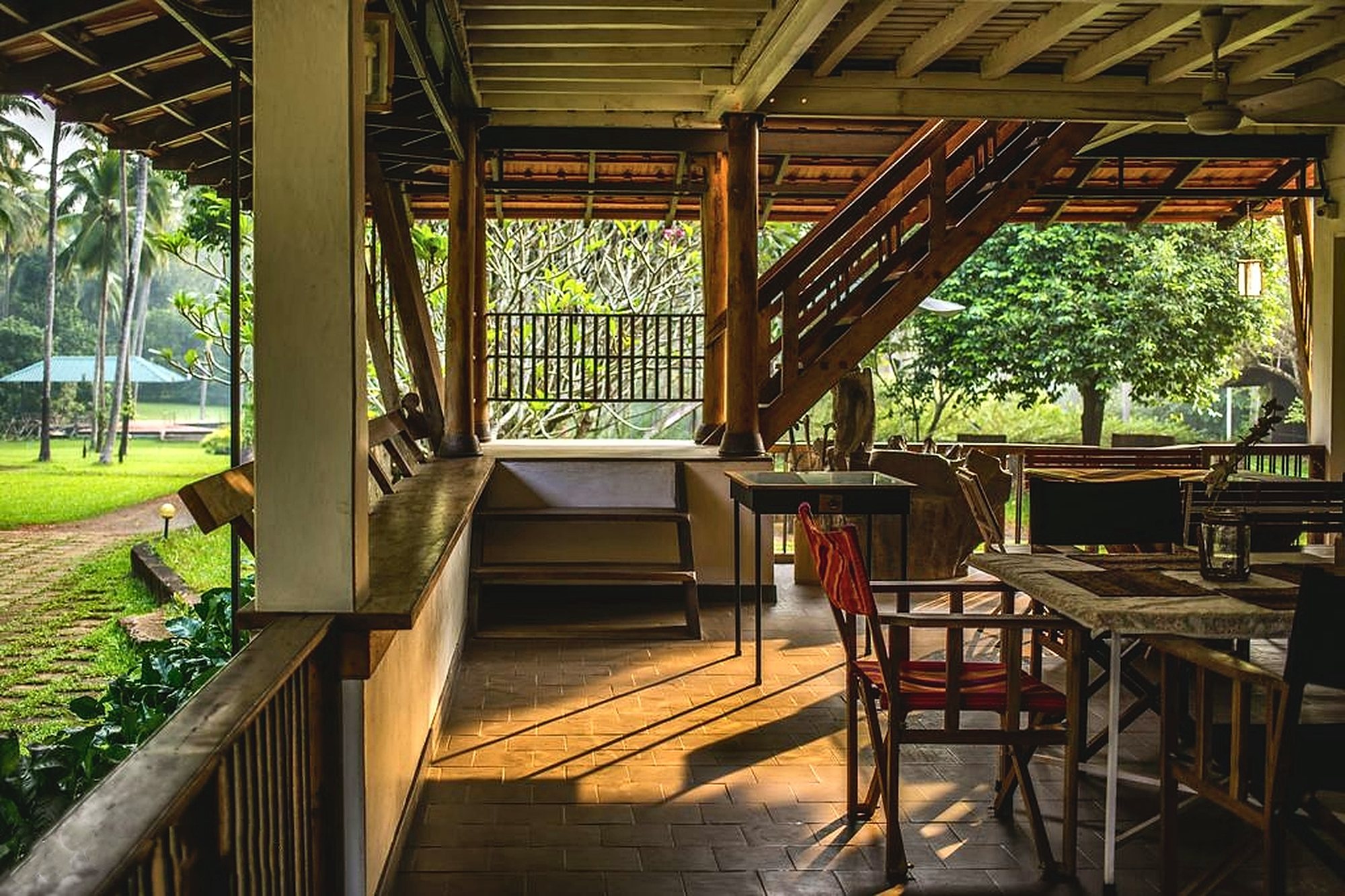 The wooden verandah, with turned timber columns, open to the lawns and palms